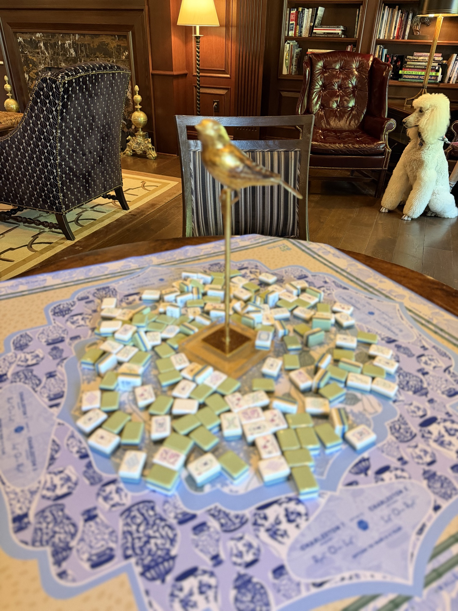 A set mahjong table with a gold sparrow at its center, in a warm sitting room